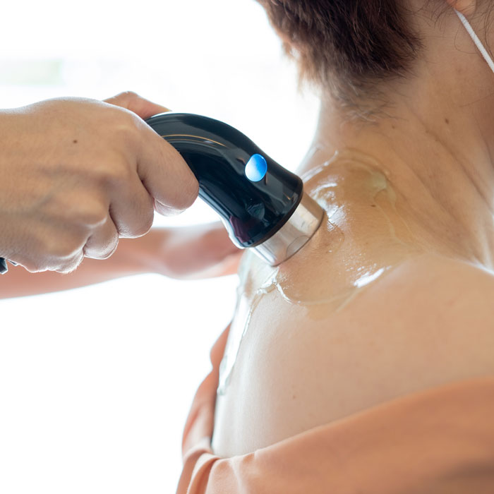 The chiropractor uses shockwave therapy on the neck to activate circulation and promote soft tissue healing.